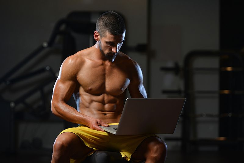 Bodybuilder sitting at laptop