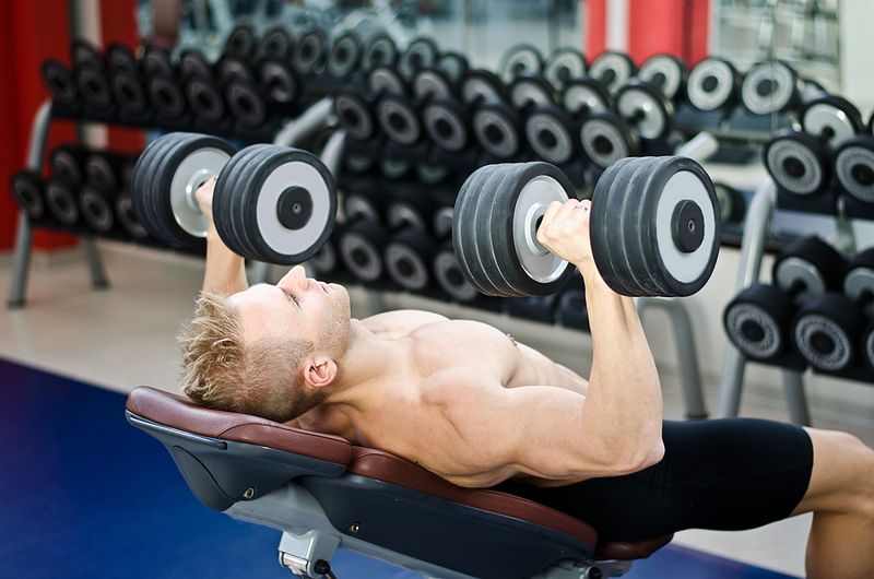 Man using round dumbbells in gym